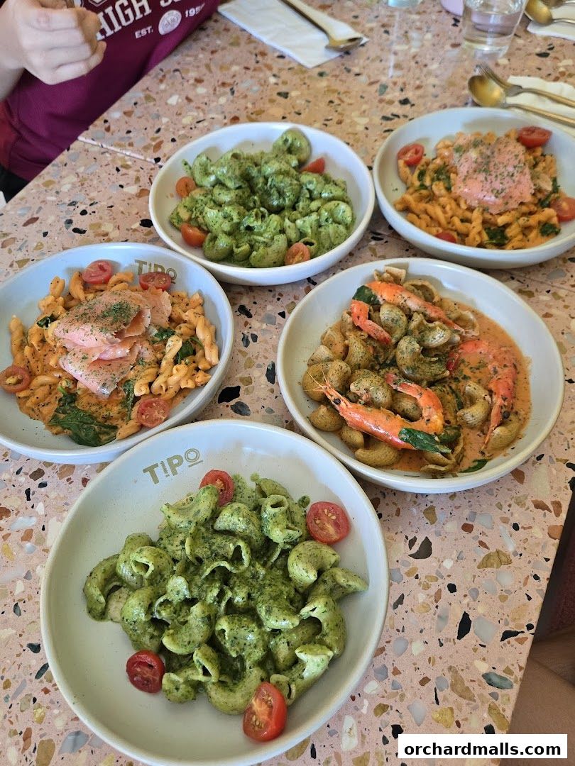 A table laden with four bowls of delicious pasta dishes, garnished with cherry tomatoes.