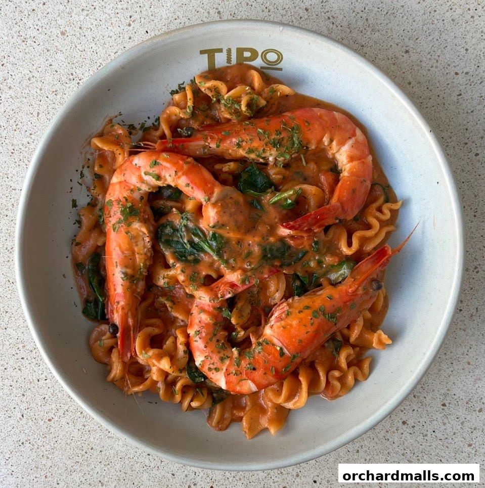 A close-up shot of a creamy prawn pasta dish with spinach, garnished with parsley.
