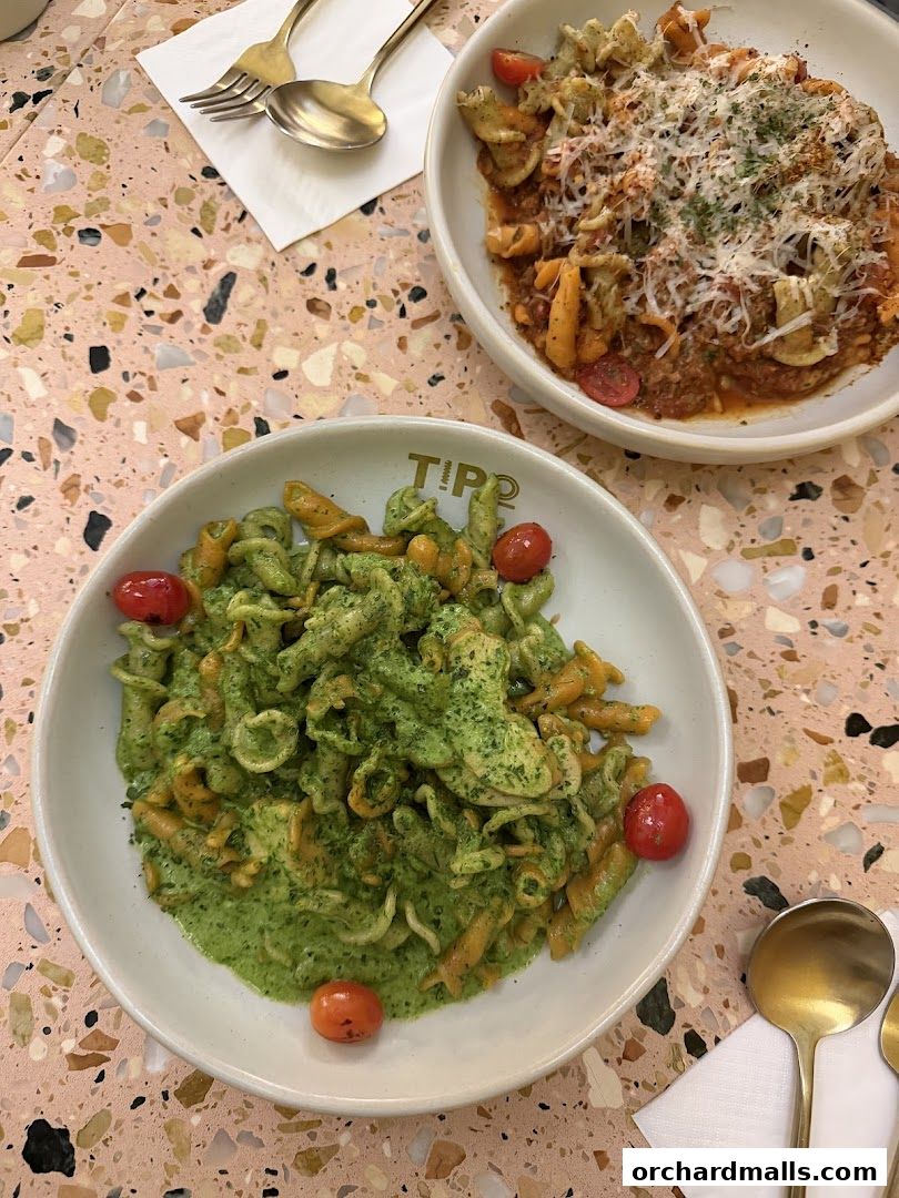Two bowls of pasta with sauce and cherry tomatoes on a terrazzo table.