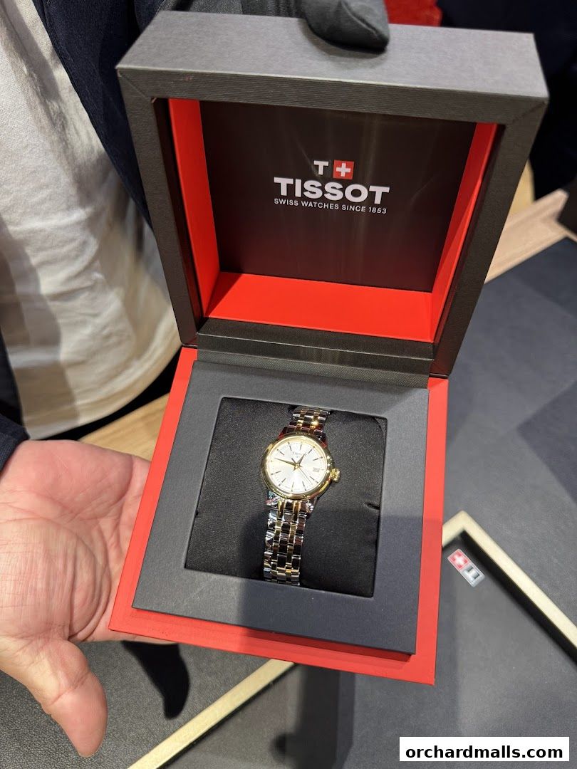 A Tissot watch in its branded box, presented by a gloved hand.
