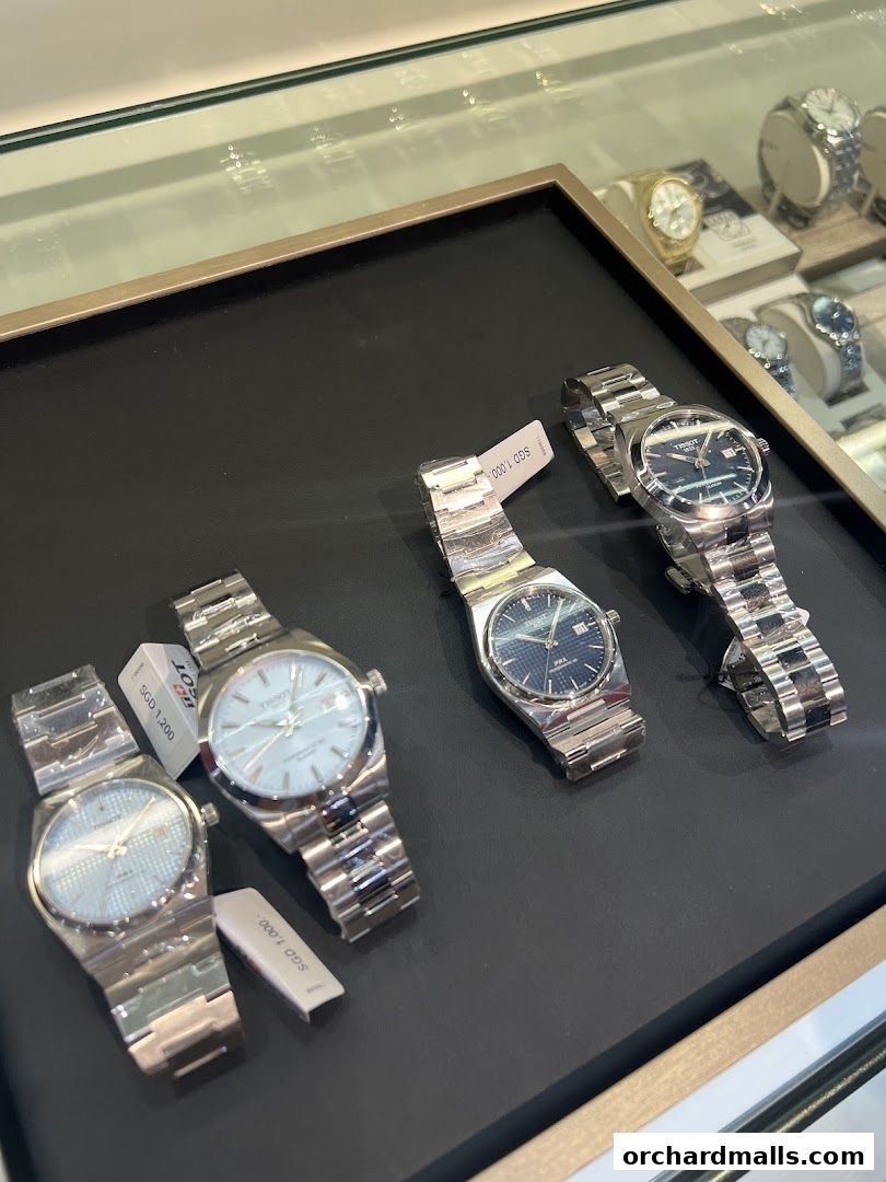 A display of Tissot watches with price tags in a store window.
