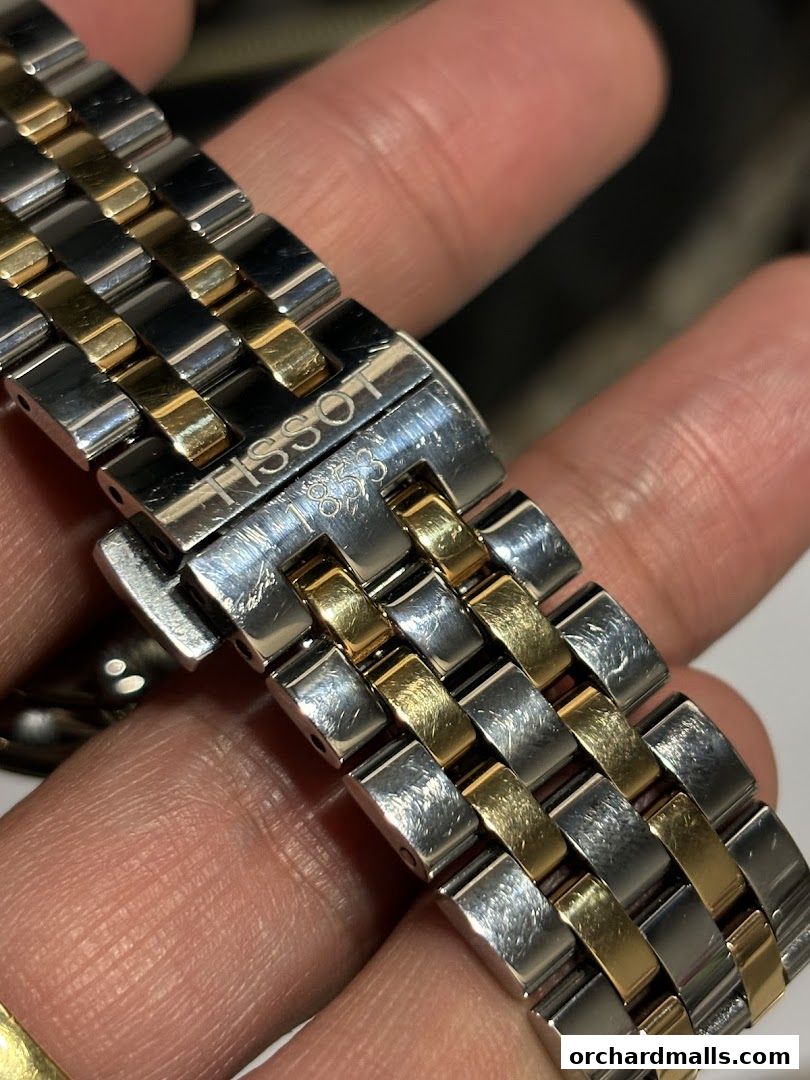 Close-up of a Tissot watch band with silver and gold-toned links.