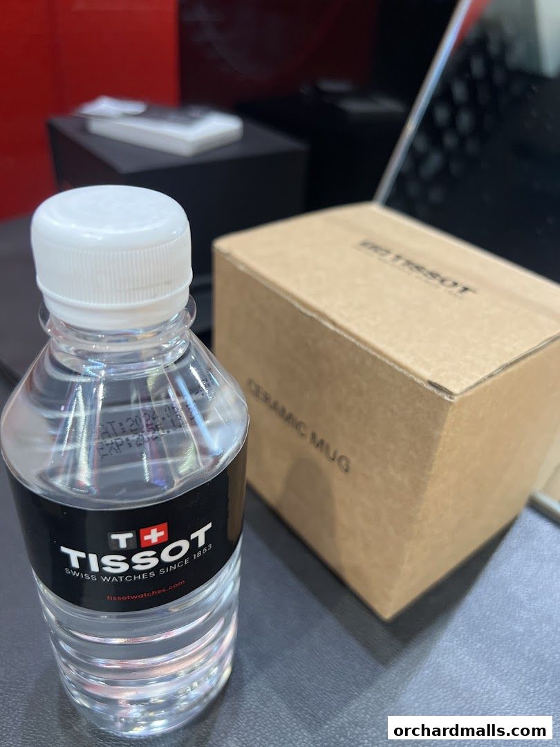 A bottle of water and a Tissot ceramic mug box are displayed on a surface.
