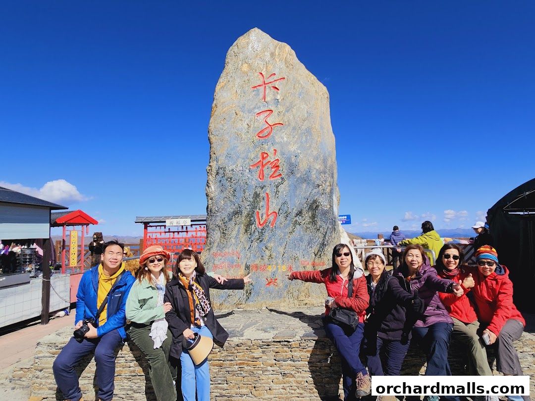 A group of tourists poses for a photo in front of a large stone monument with Chinese inscriptions.