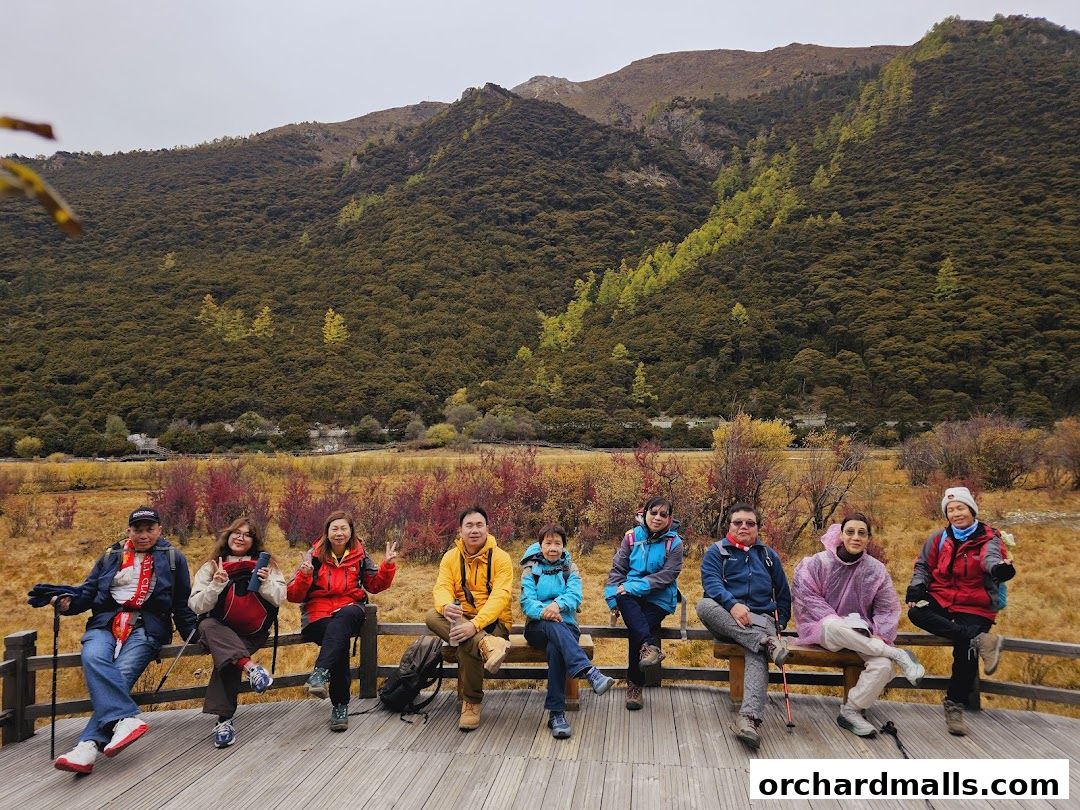 A group of people in outdoor gear posing for a photo with a scenic mountain backdrop.