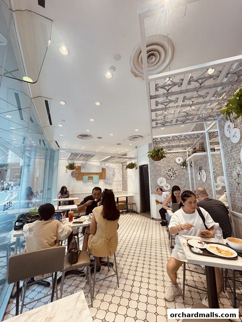 Diners enjoy meals inside a bright and modern cafe with patterned floors and decorative walls.