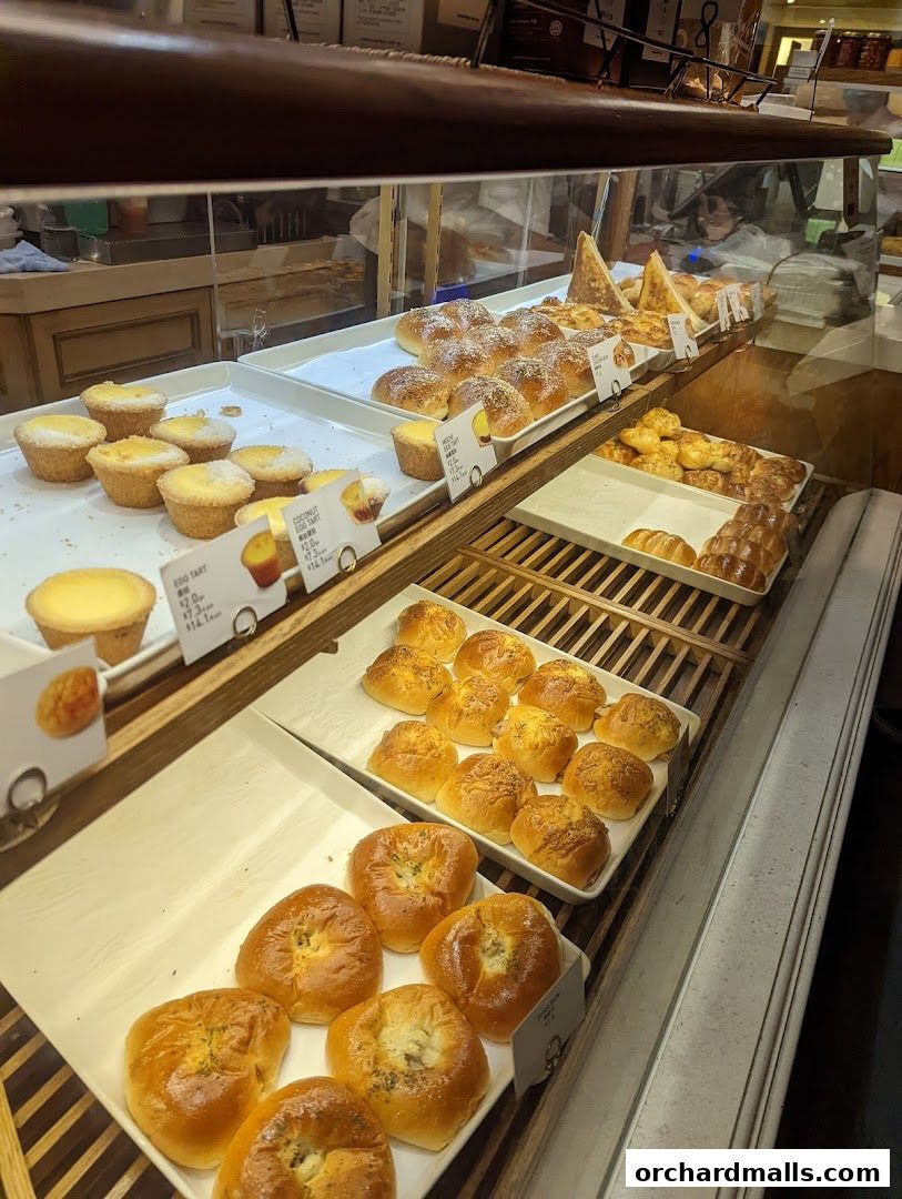 A display of freshly baked pastries and buns in a bakery case.