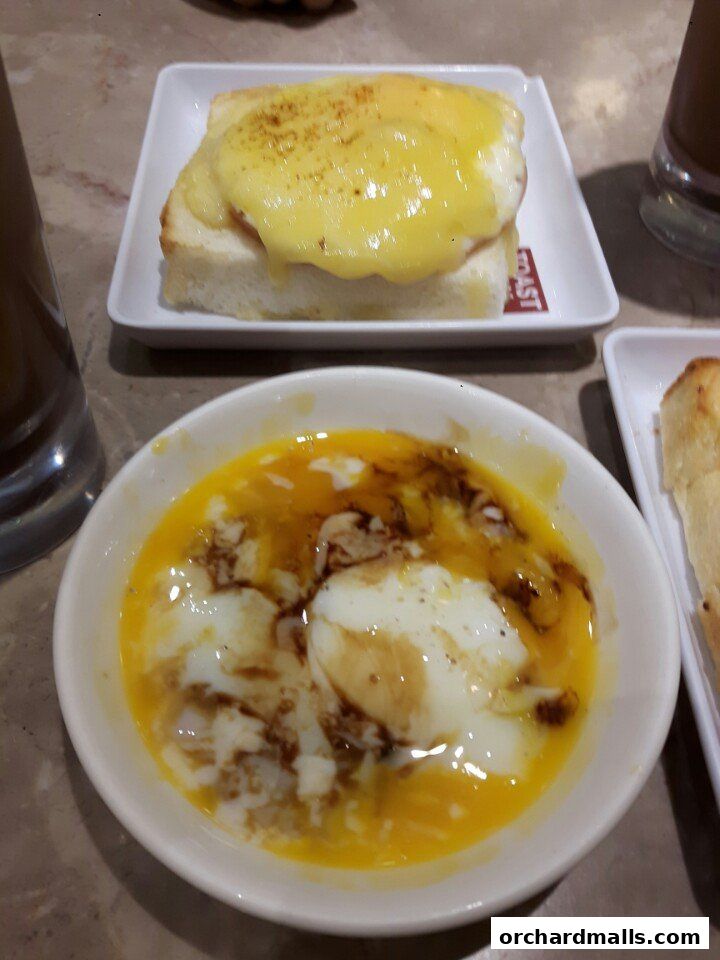 A close-up of two delicious breakfast dishes: soft-boiled eggs and toast with melted cheese.