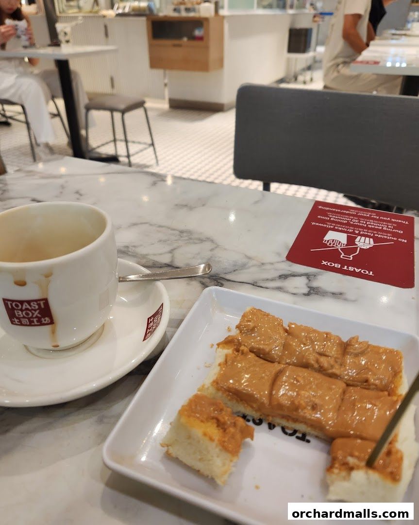 A cup of coffee and peanut butter toast served on a marble table at Toast Box.