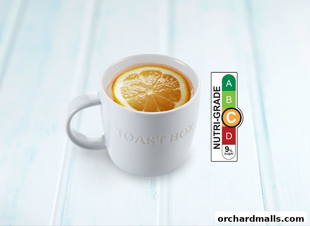 A white mug with 'Toast Box' embossed on it, filled with tea and a lemon slice.