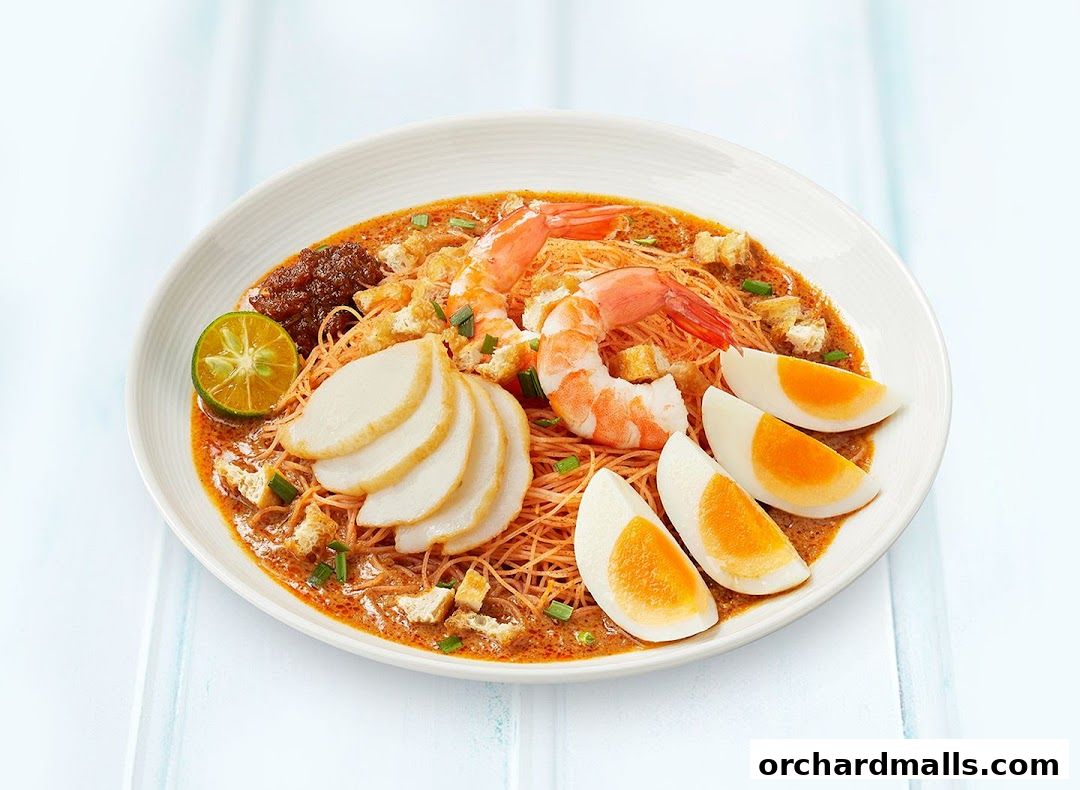 A delicious bowl of Laksa with prawns, fish cake, egg, and lime.