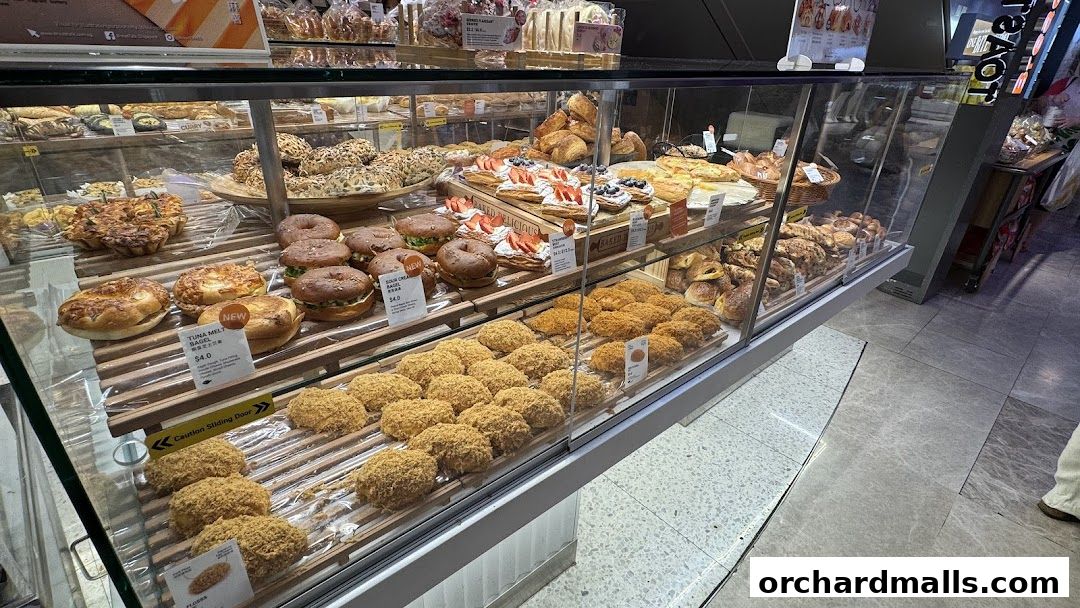 A display case filled with various baked goods, including bagels, pastries, and buns.