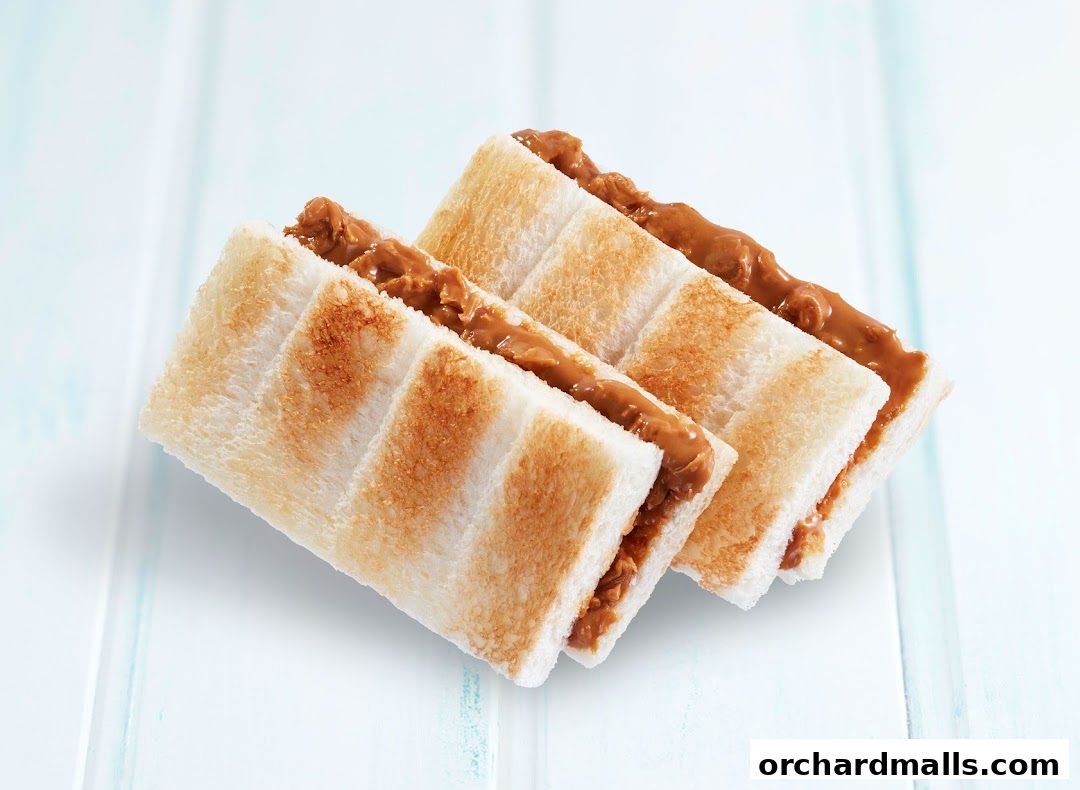 Three slices of toasted bread filled with creamy peanut butter, presented on a light blue surface.