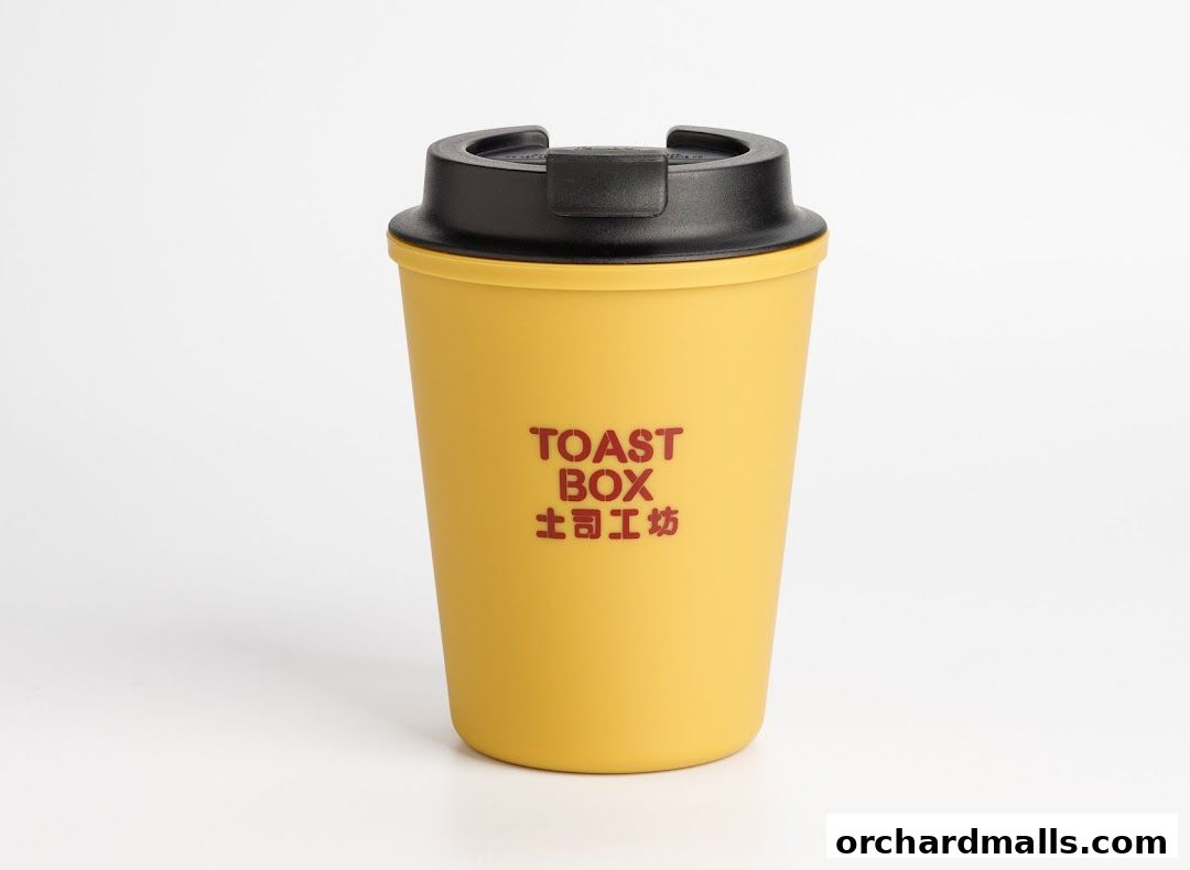 A yellow reusable coffee cup with a black lid, featuring the Toast Box logo.