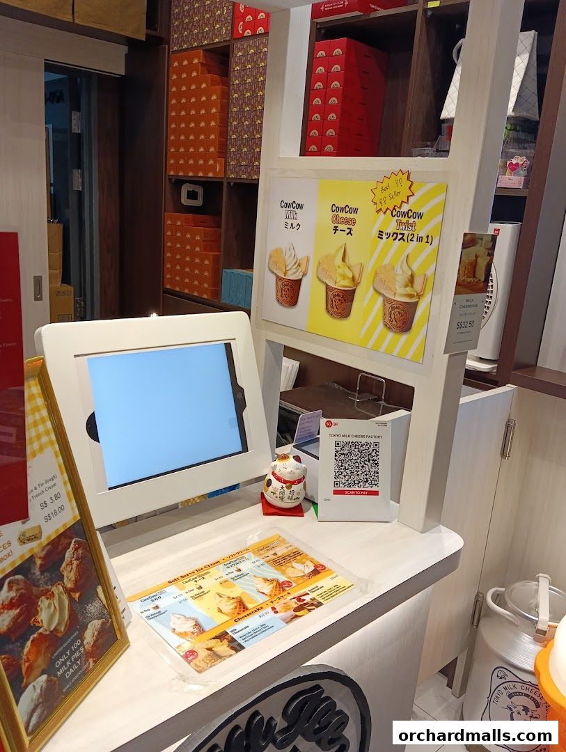 A display counter at Tokyo Milk Cheese Factory with a menu, touchscreen, and product packaging.