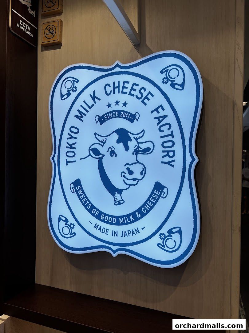 A glowing sign for Tokyo Milk Cheese Factory, featuring a cow and text.