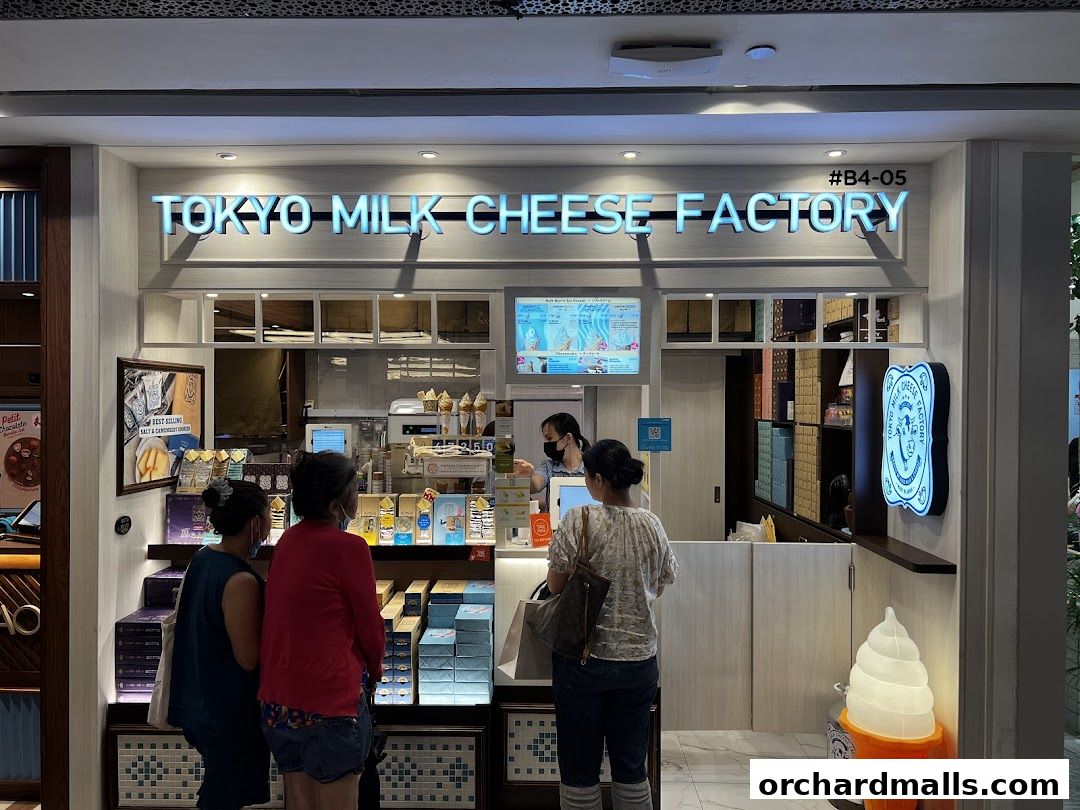 Customers at the Tokyo Milk Cheese Factory counter, with products displayed and an ice cream cone decoration.