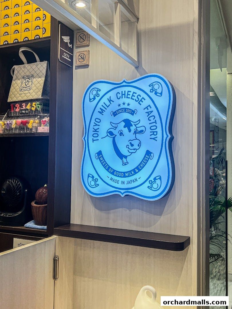 A glowing blue sign for Tokyo Milk Cheese Factory with a cow illustration.