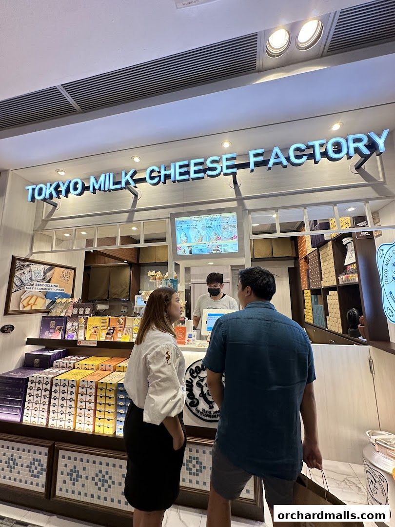 Customers at the Tokyo Milk Cheese Factory counter, with products displayed.