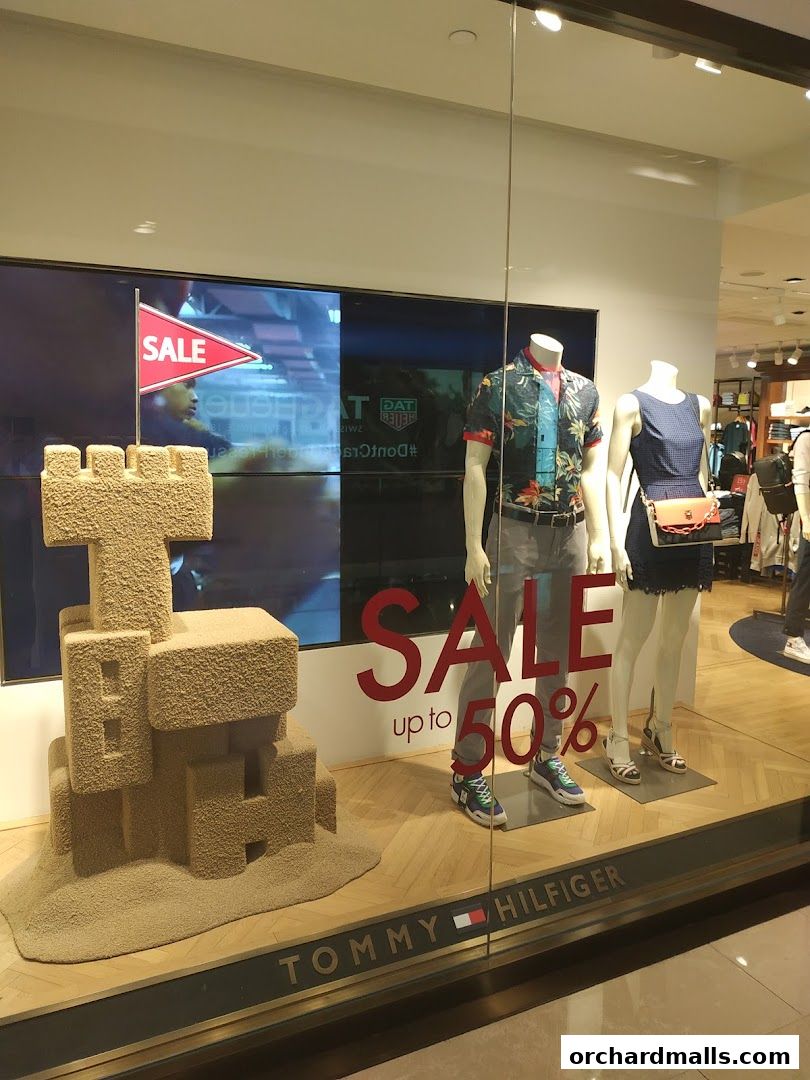 Tommy Hilfiger store window display featuring mannequins and a large sale sign.