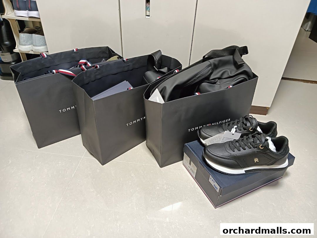 Tommy Hilfiger shopping bags and a pair of black sneakers on a box.