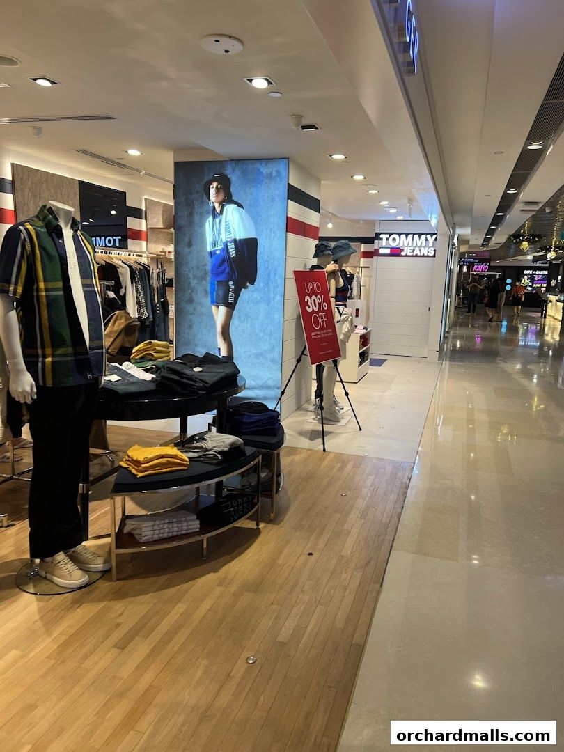 Interior of a Tommy Hilfiger store with mannequins, clothing displays, and a "Up to 30% Off" sign.