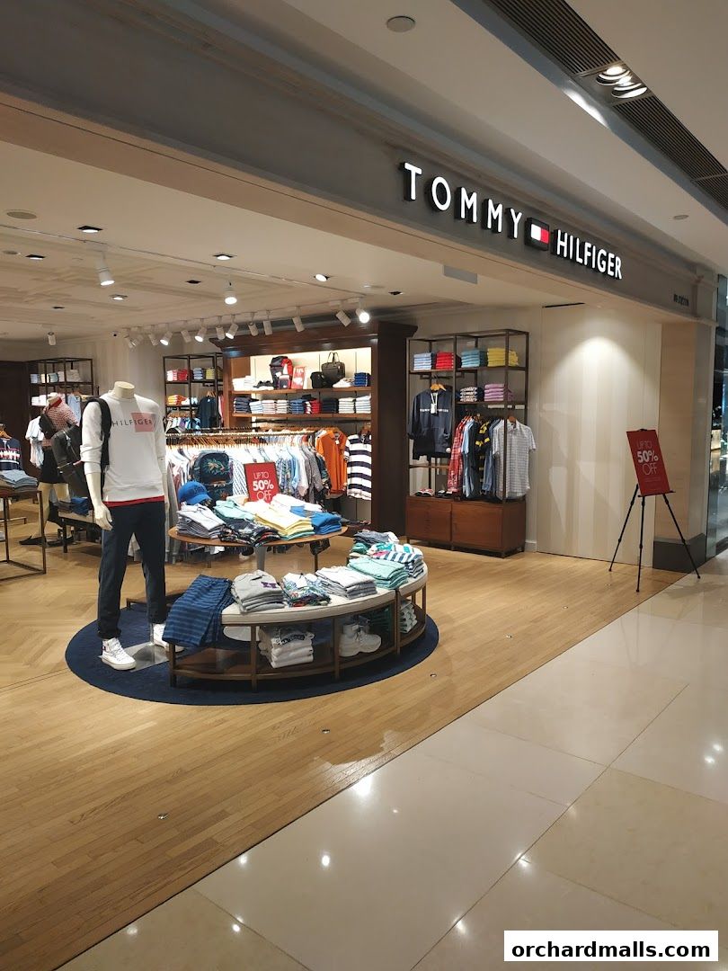 Interior of a Tommy Hilfiger store showcasing clothing on mannequins and racks, with a sale sign.