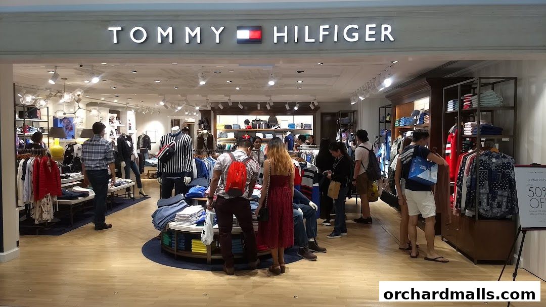 Customers browse clothing inside a brightly lit Tommy Hilfiger store.