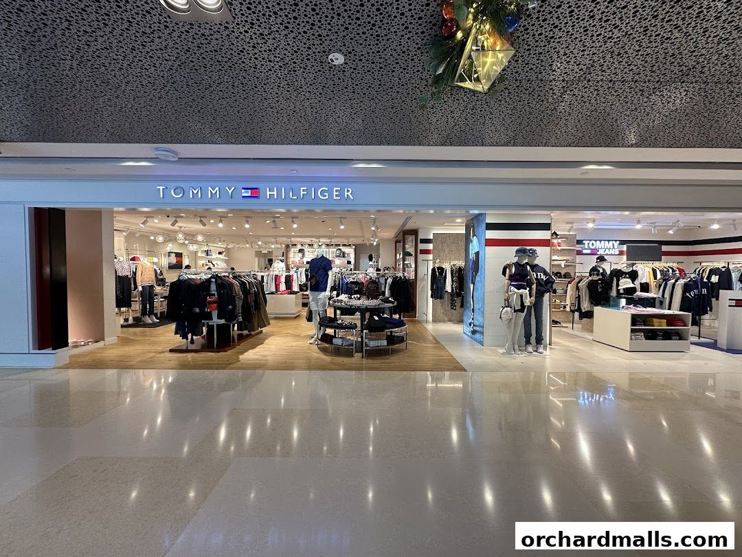 The entrance of a Tommy Hilfiger store showcasing apparel on racks and mannequins.