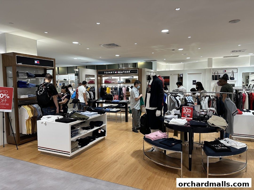 Interior of a Tommy Hilfiger store with clothing displays and shoppers.