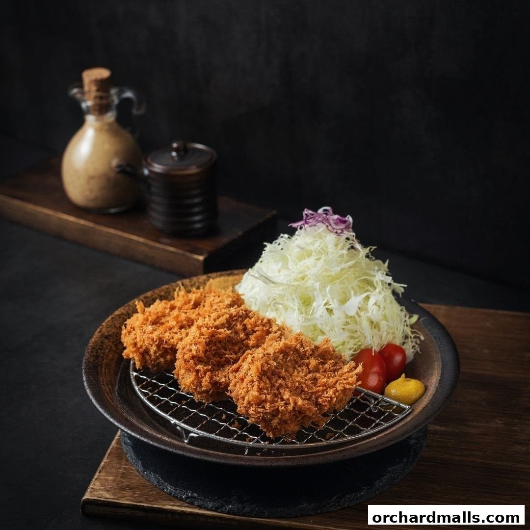 Crispy Tonkatsu served with shredded cabbage, cherry tomatoes, and mustard.