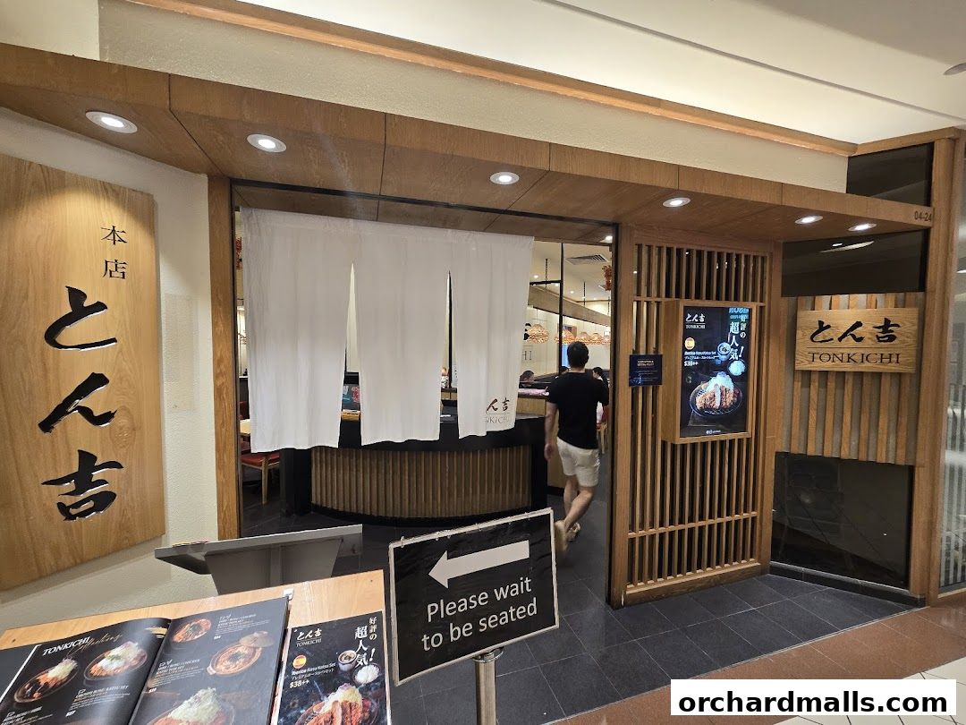 The entrance to Tonkichi, a Japanese restaurant, with a sign and a person entering.