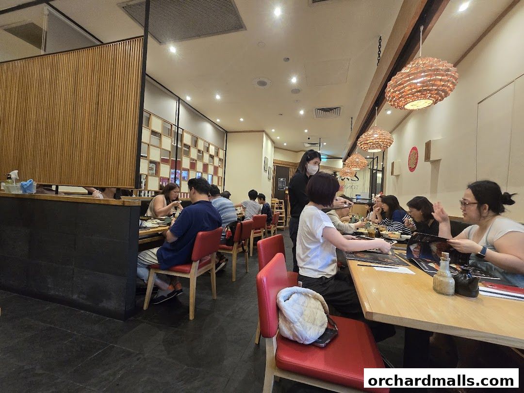 Diners seated at tables in a restaurant with warm lighting and wooden accents.