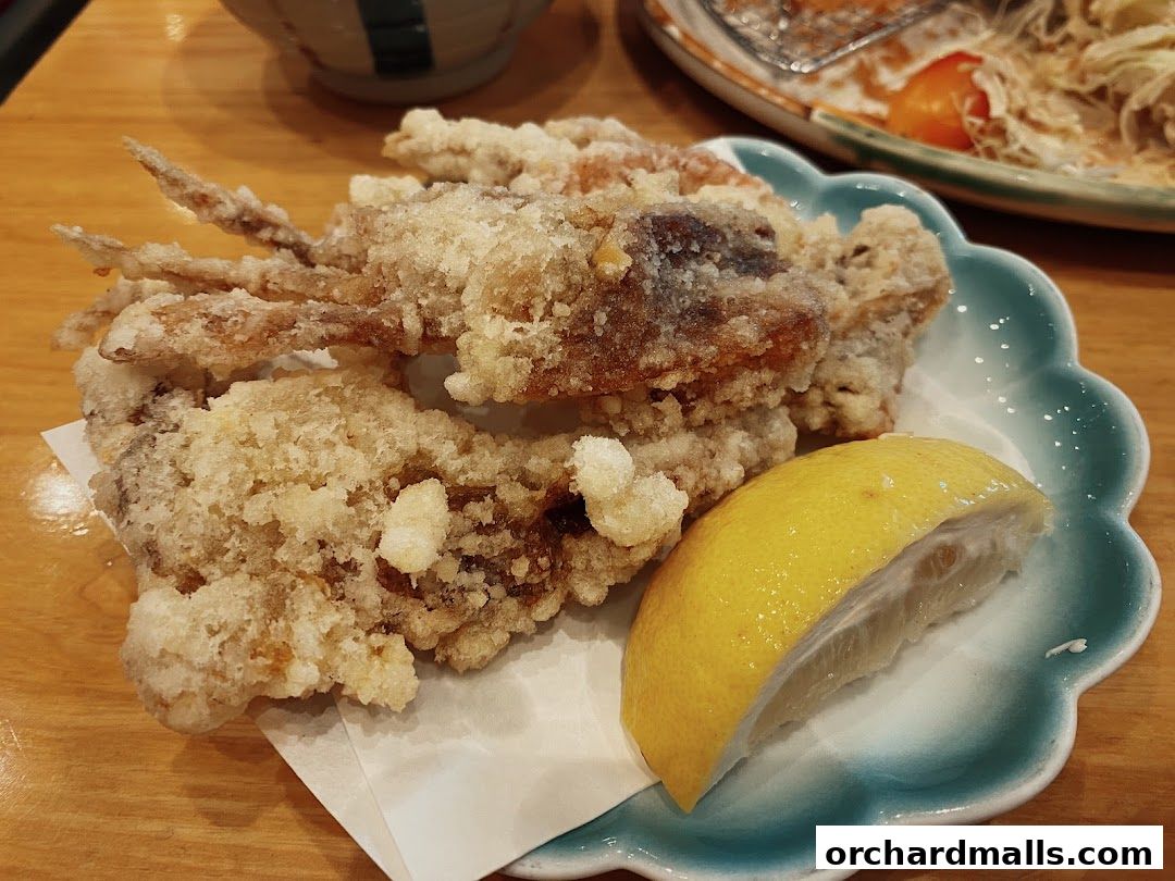 Crispy fried soft shell crab served with a lemon wedge on a decorative plate.