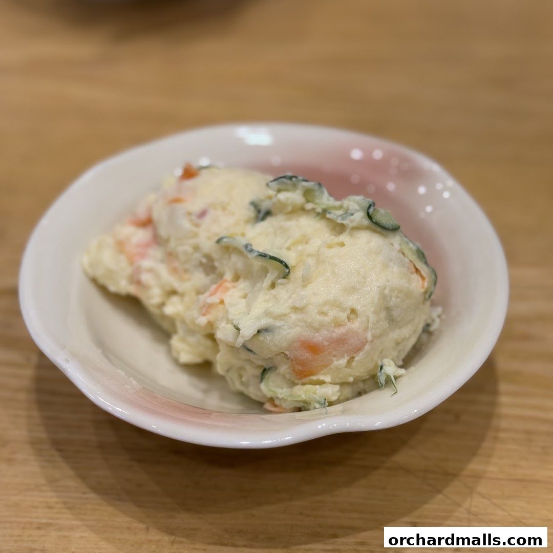 A close-up of a creamy potato salad with visible pieces of cucumber and carrot.