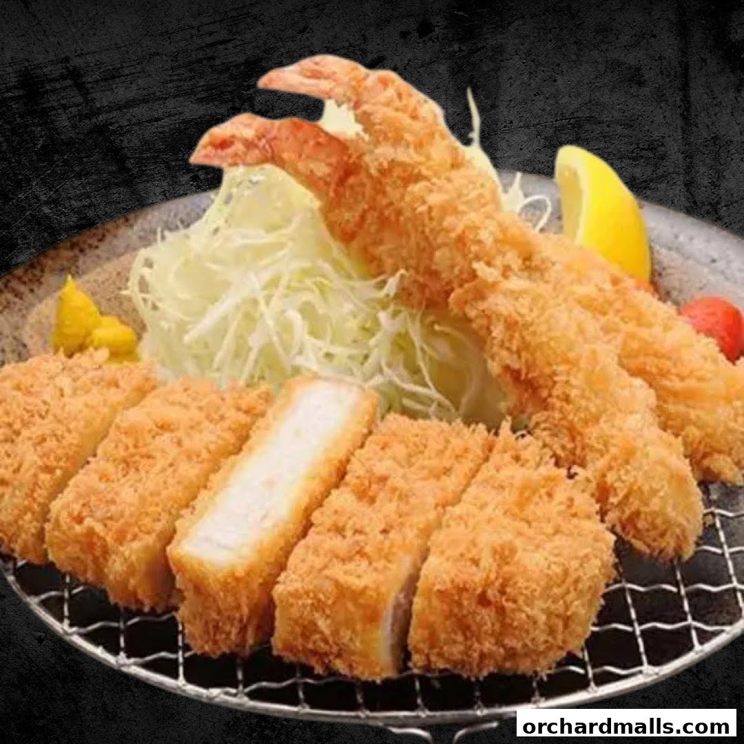 A plate of crispy fried pork cutlet and shrimp served with shredded cabbage and lemon.