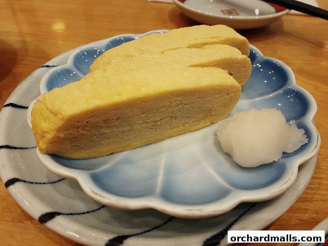 A close-up of tamagoyaki, a Japanese rolled omelet, served with grated daikon radish.
