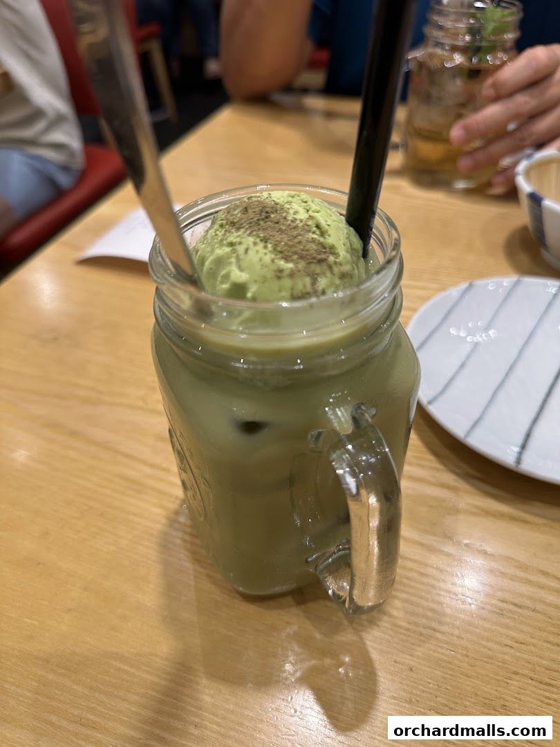 A refreshing matcha ice cream float served in a mason jar with a spoon and straw.
