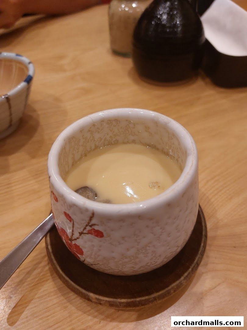A close-up of a steaming bowl of chawanmushi with a decorative pattern.