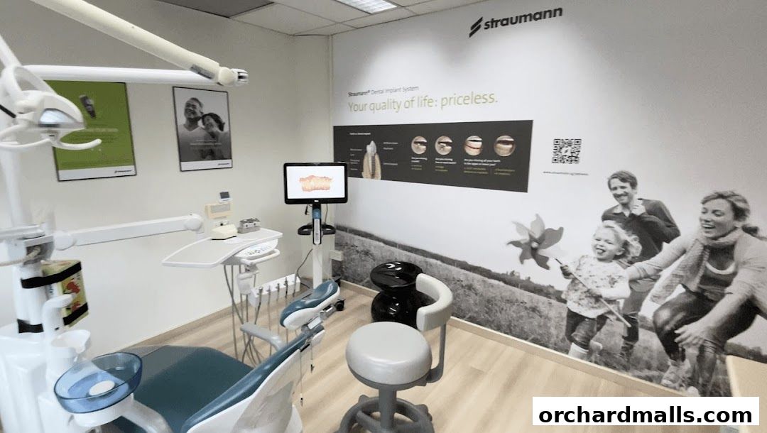 A modern dental examination room with a chair, equipment, and informative wall graphics.