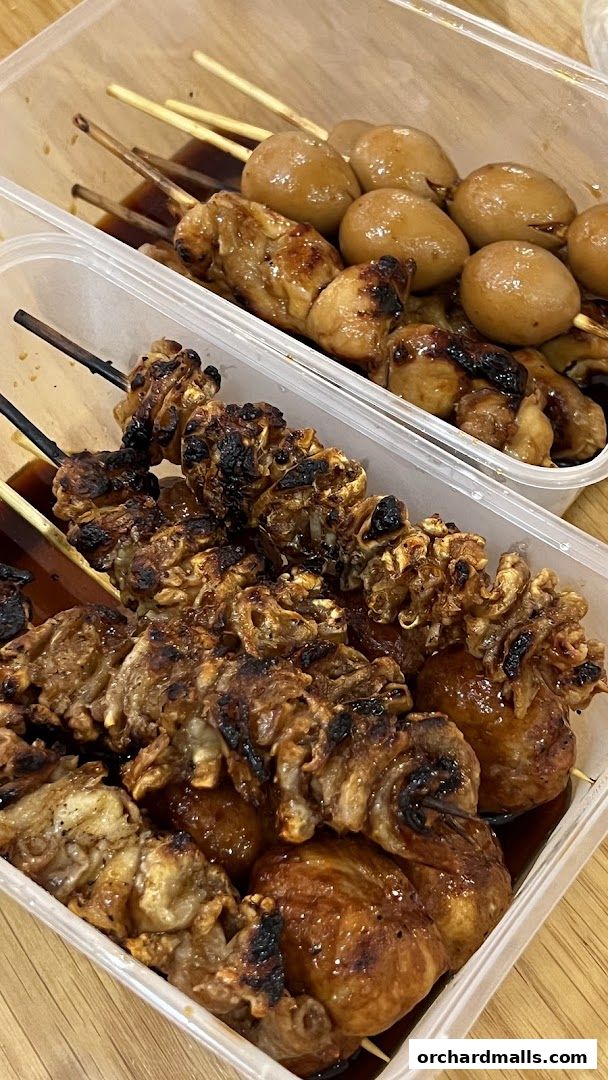 Two containers of grilled skewers with a glossy sauce, featuring chicken and quail eggs.
