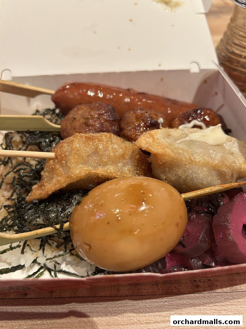 A close-up of a bento box filled with various skewers and rice.
