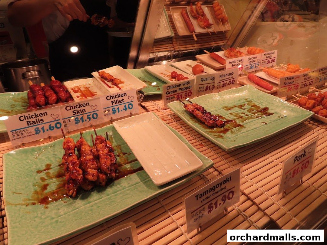 A display of various Japanese skewers and snacks with price labels.