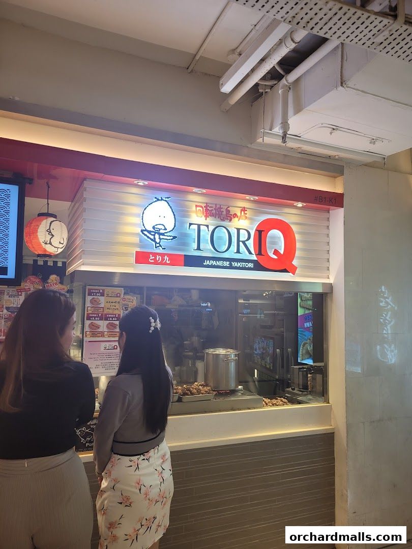 Two women stand in front of the TORI-Q Japanese Yakitori shop.