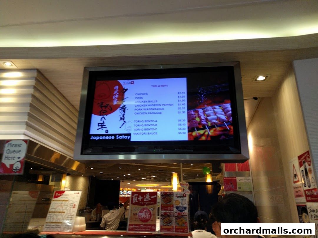 A digital menu board displaying Japanese Satay items and prices at TORI-Q.