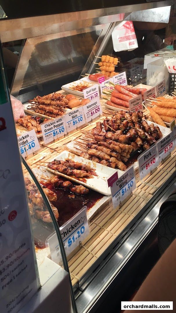 A display case filled with various grilled skewers and sausages at TORI-Q.