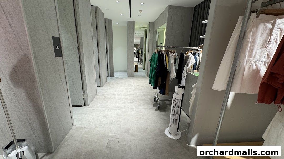 Interior view of a modern clothing store with fitting rooms and clothing racks.