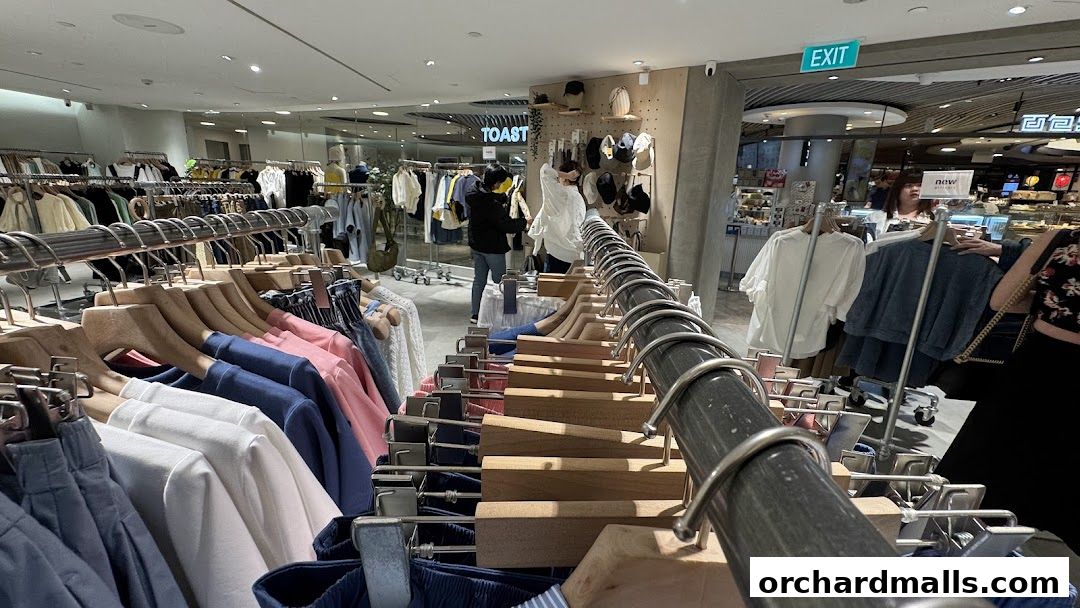 Interior view of a clothing store with racks of apparel and shoppers browsing.
