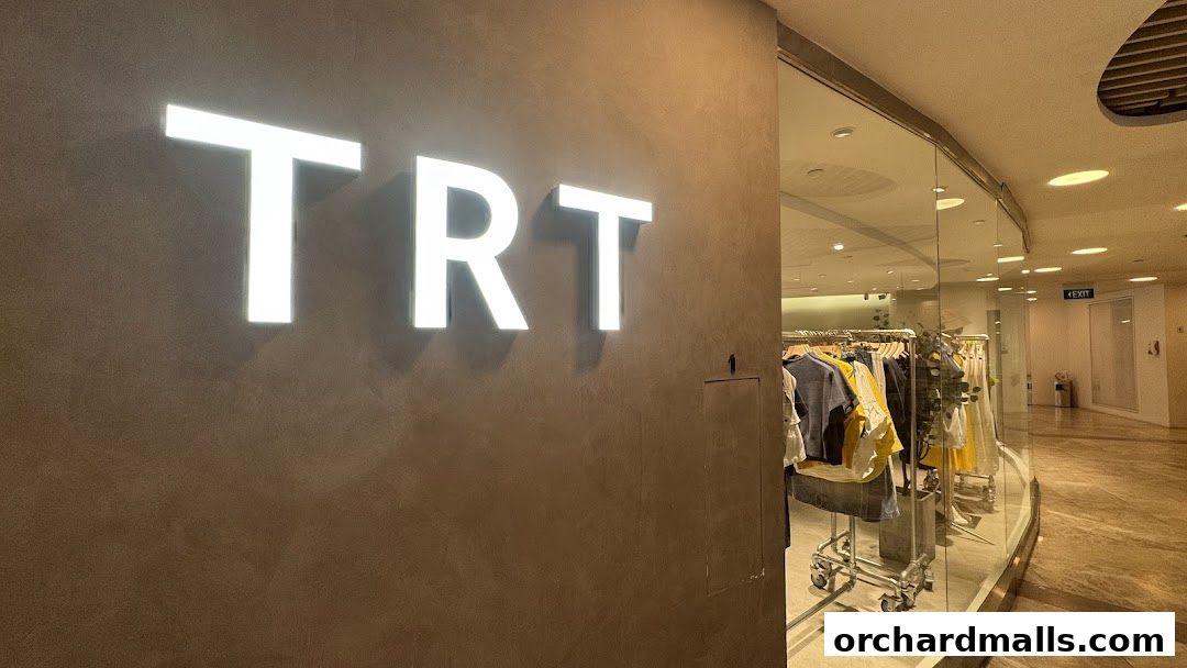 The illuminated 'TRT' logo on a textured wall next to a clothing store display.