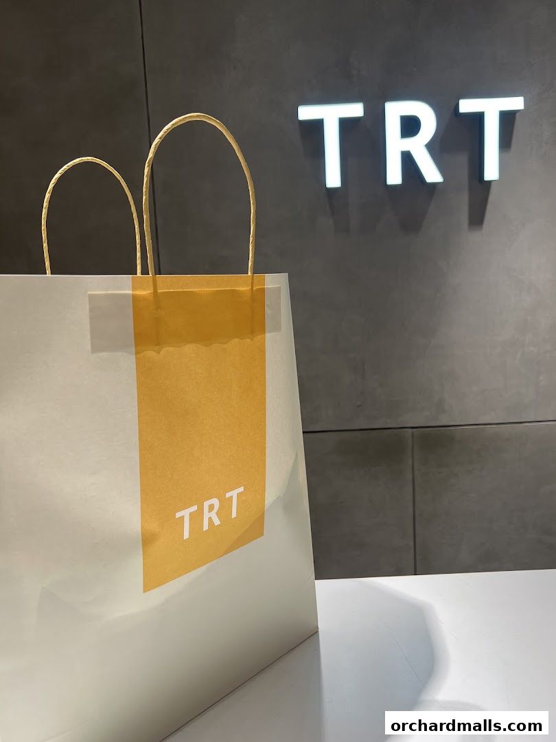A shopping bag with the TRT logo in front of the store's illuminated sign.